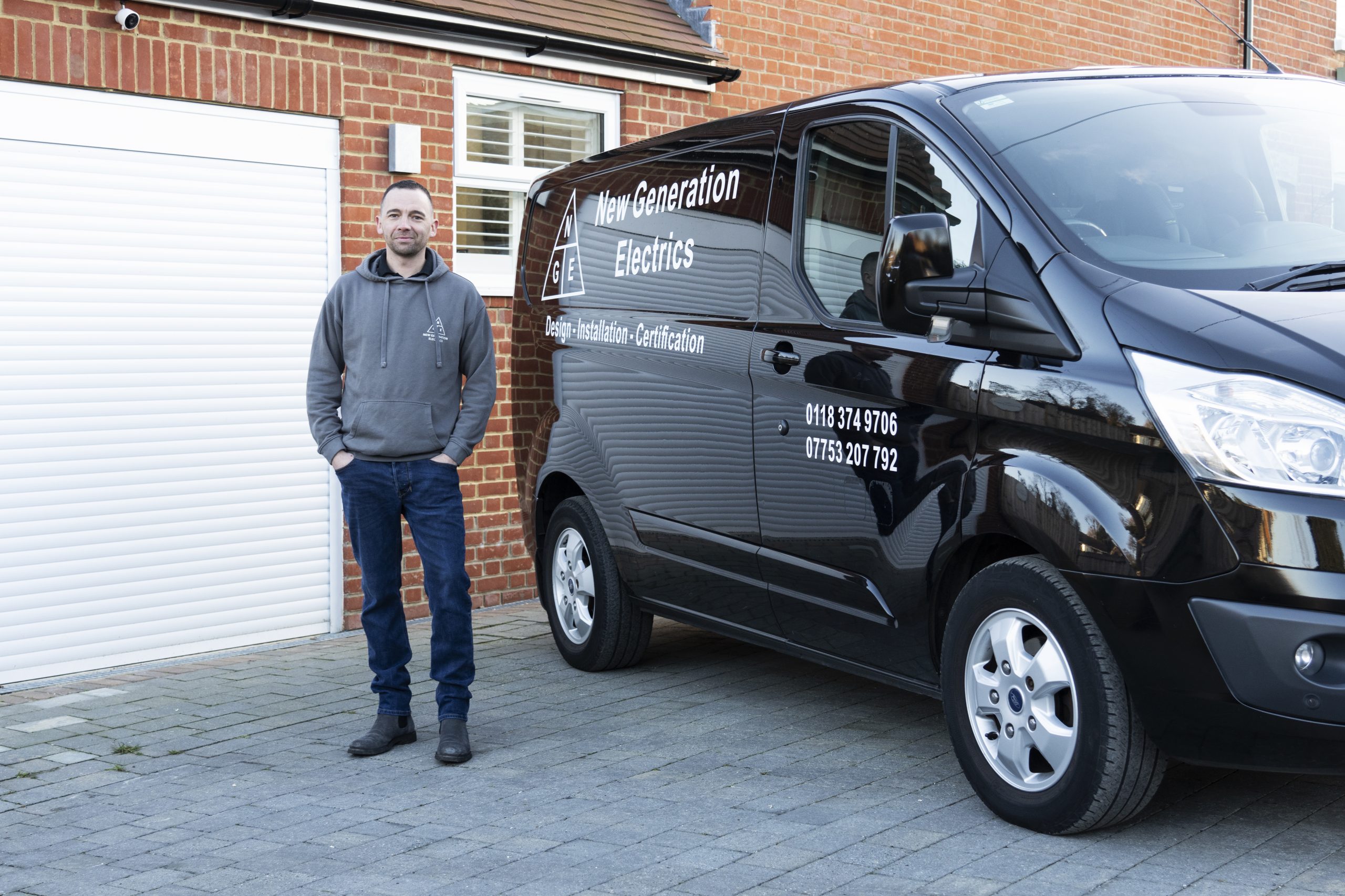 "Danny White from New Generation Electrics standing beside a branded van, providing electrical services in Reading and Berkshire"